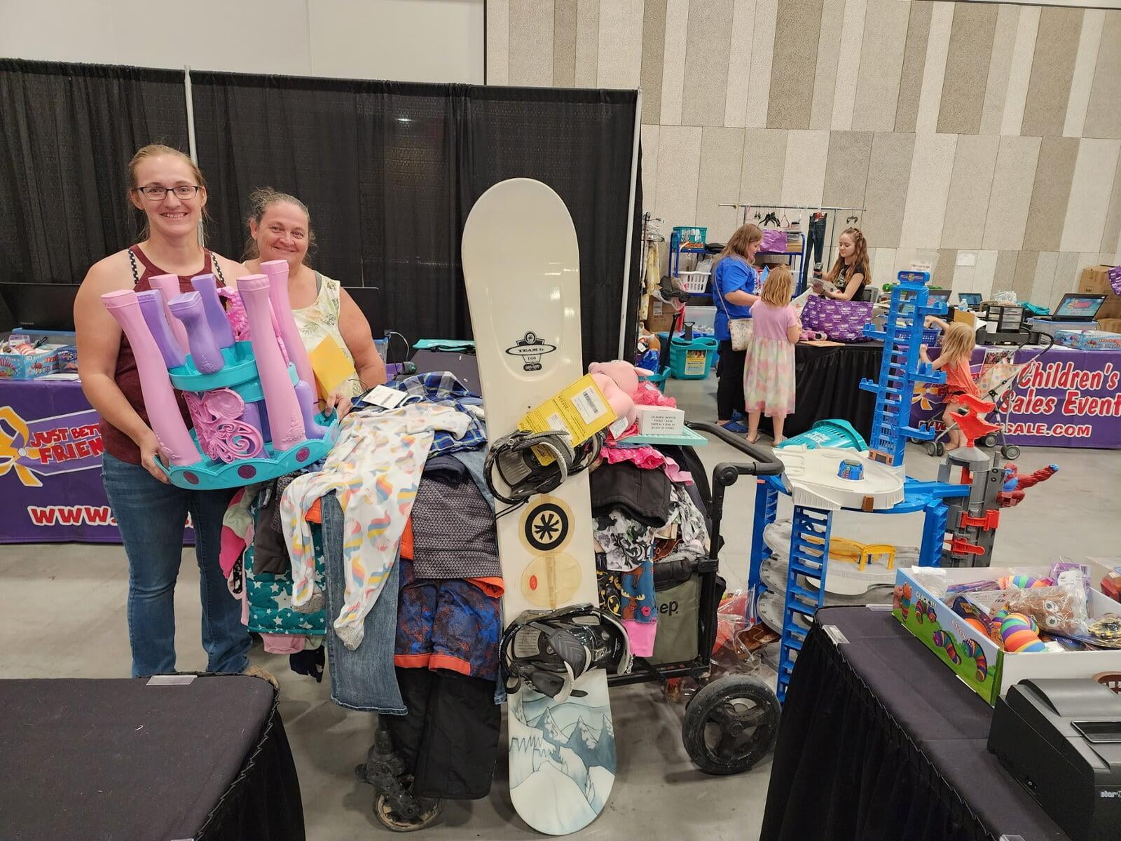 A mom shops a row of girls clothing with a wagon full of clothing